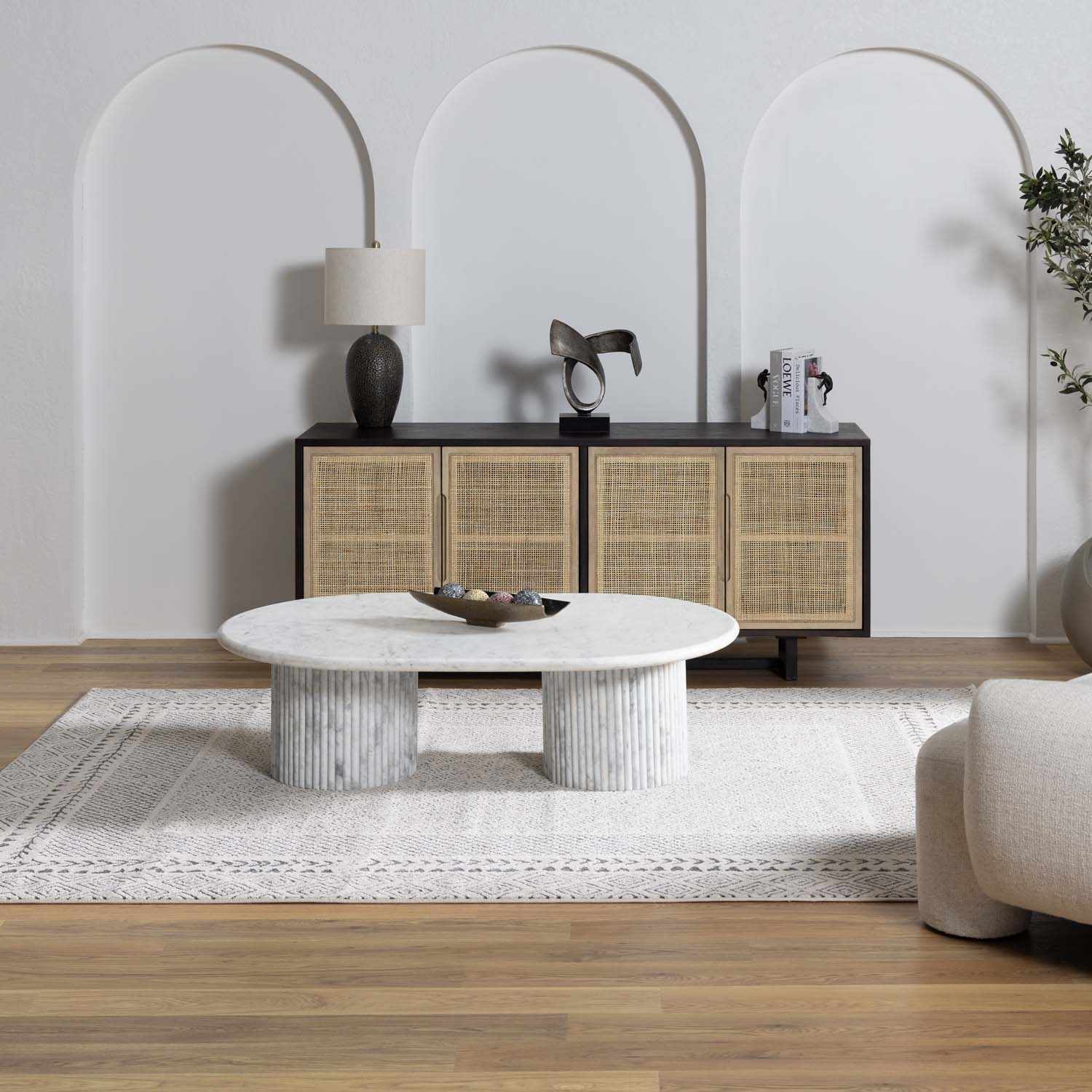 Living room scene with Burdette Soft Neutral Rug, marble coffee table, and cane cabinet against arched wall. Roomscene-Rectangle