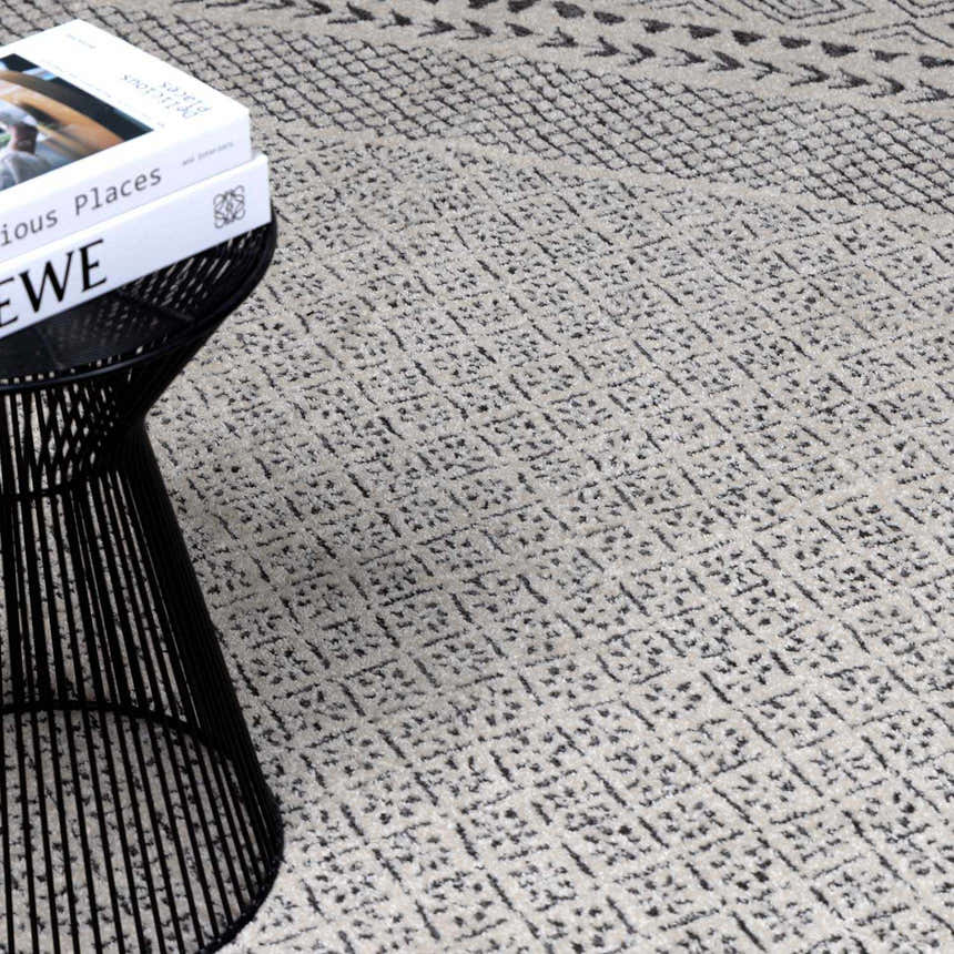 Close-up of Burdette Soft Neutral Rug showing a geometric diamond pattern in charcoal, gray, and off-white. Styleshot