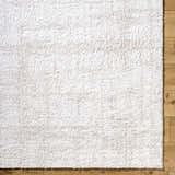 Close-up of the Bianca Area Rug showing its white shag texture on light wood floors. Corner