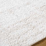 Close-up of the Bianca Area Rug, a white shag rug with a soft, textured pile on wood flooring. Texture