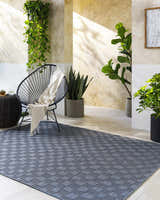 Sunlit patio with plants, modern chair, and gray geometric Arifah Area Rug. Roomscene-Rectangle