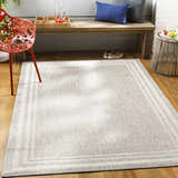 Entryway scene with a beige Burradoo Bordered Area Rug, wooden bench with pillows, and a bright red chair. Roomscene-Rectangle