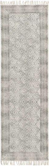 Close-up of the Brushton Area Rug. Beige cotton rug with black geometric diamond pattern and fringe. Hand woven. Design-Runner-268