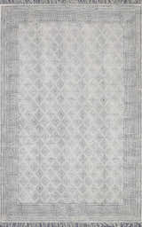 Close-up of the Brushton Area Rug. Beige cotton rug with black diamond and floral pattern and fringed edges. Design-Rectangle