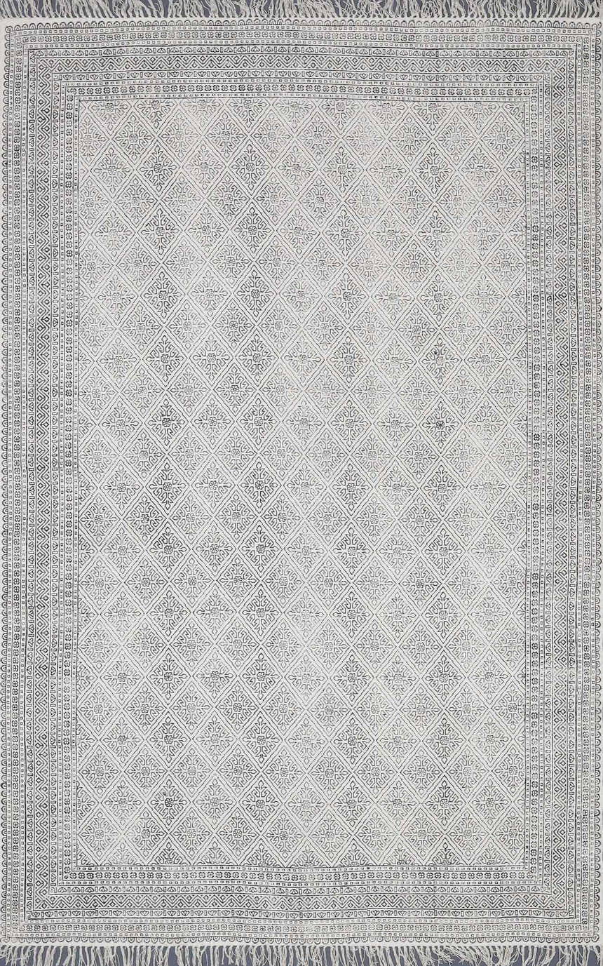 Close-up of the Brushton Area Rug. Beige cotton rug with black diamond and floral pattern and fringed edges. Design-Rectangle