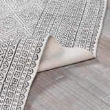 Close-up of the Brushton Area Rug, a hand-woven cotton rug in beige and black with a geometric, bohemian-inspired pattern. Fold