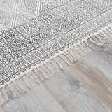 Close-up of the Brushton Area Rug. Beige cotton rug with black geometric pattern and fringe. Hand woven rug. Pile
