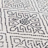 Close-up of the Brushton Area Rug showing its hand-woven texture and geometric black and beige pattern. Texture