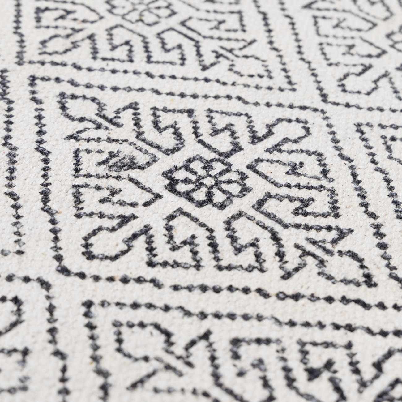 Close-up of the Brushton Area Rug showing its hand-woven texture and geometric black and beige pattern. Texture