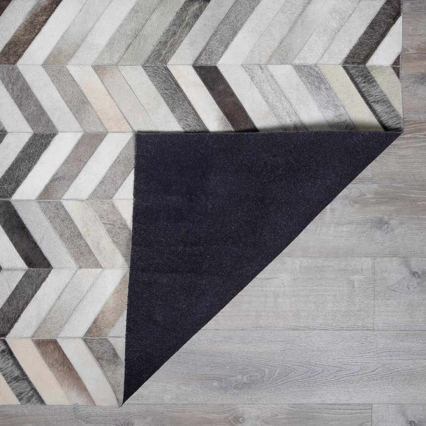 Close-up of Bristolville Premium Leather Rug. Hair on hide rug with a contemporary chevron pattern in shades of gray, tan and white. Fold