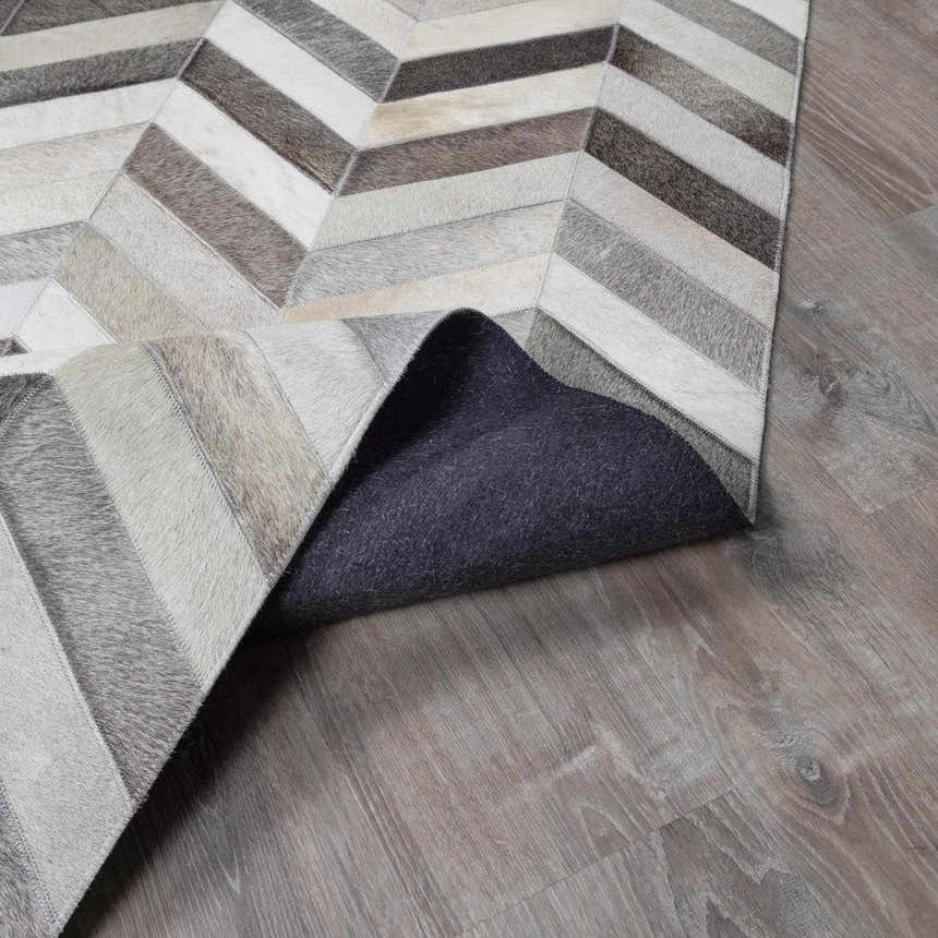 Close-up of the Bristolville Premium Leather Rug featuring a gray, tan, and brown chevron pattern. Fold