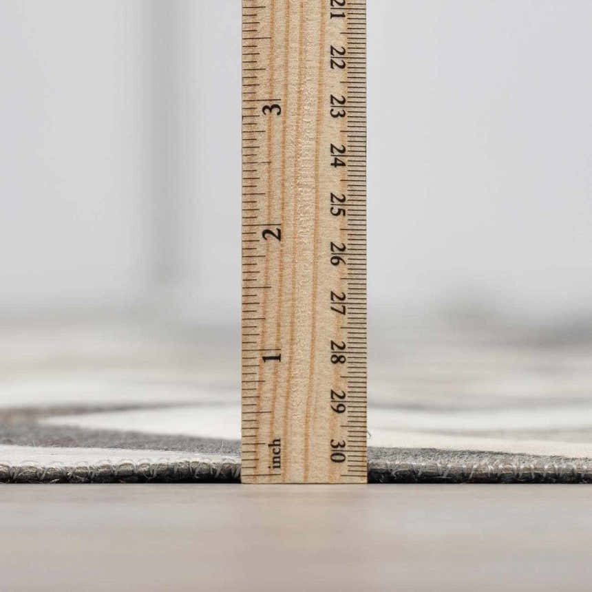Close-up of the Bristolville Premium Leather Rug showing the pile height with a ruler. Gray and white tones. Pile