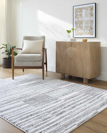 Living room scene with gray armchair and Bashar Area Rug in black, ivory and gray stripes. Roomscene-Rectangle