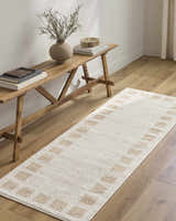 Entryway scene with a Beynon Beige Washable Area Rug runner, rustic wood bench, vase, books, and light wood floors. Roomscene-Runner