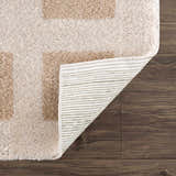 Close-up of the Beynon Beige Washable Area Rug showing its beige and peach geometric design and machine woven construction. Fold