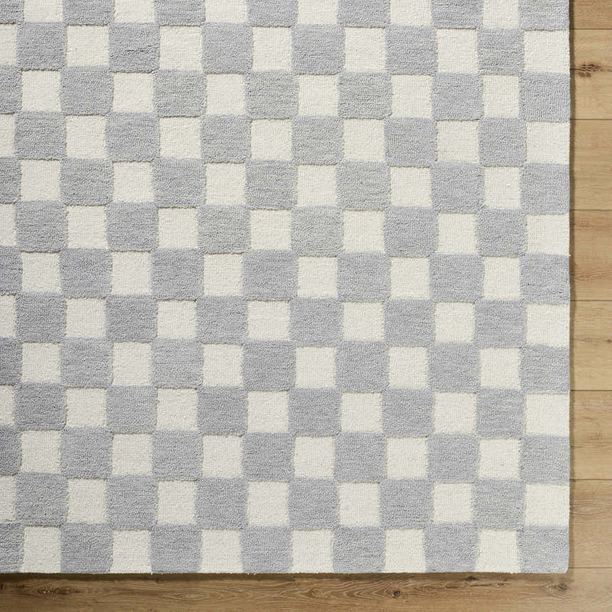 Close-up of the hand-tufted Amparo Medium Gray Area Rug. Ivory and medium gray checkerboard pattern, 100% wool texture. Corner