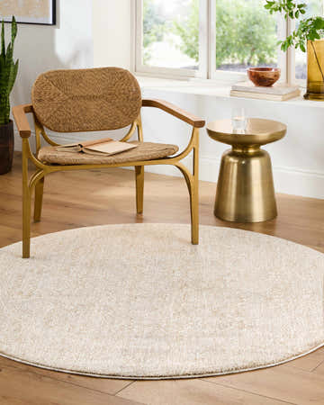 Light and airy room scene with a round Beiwen Area Rug in light sage, woven chair, and gold accent table. Roomscene-Round