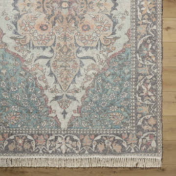 Close-up of the hand-loomed Bohdan Teal Area Rug. Features traditional floral patterns in teal, peach, ivory, and pink. Corner