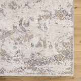 Close-up of the Breeda Charcoal Area Rug. Southwestern style rug in charcoal, cream, ivory, olive, and tan on a wood floor. Corner