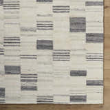 Close-up of Max Handmade Becki Owens x LIVABLISS BOMX-2305 Area Rug. Cream wool rug with ash, blue, and charcoal geometric design. Corner