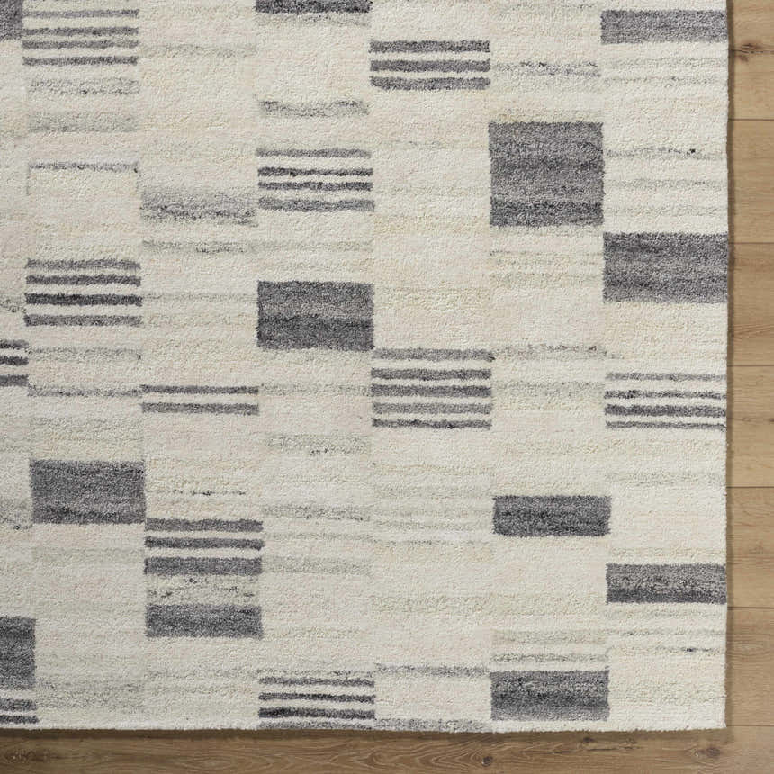 Close-up of Max Handmade Becki Owens x LIVABLISS BOMX-2305 Area Rug. Cream wool rug with ash, blue, and charcoal geometric design. Corner