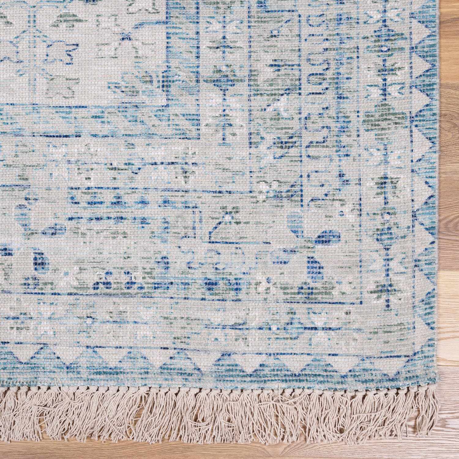 Close-up of the Byers Handmade Cotton-blend Aqua Rug showing its woven texture, blue and green patterns, and fringe. Swatch
