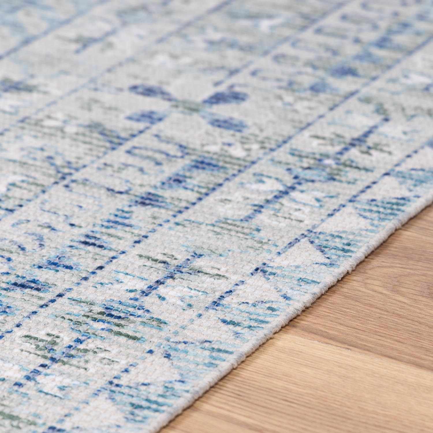 Close-up of Byers Handmade Cotton-blend Aqua Rug showing its hand woven texture and blue, green, and white pattern. Texture