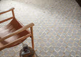 Living room scene with a tan leather chair on a Byng Premium Rug. The rug has a cream and gray geometric pattern. Styleshot