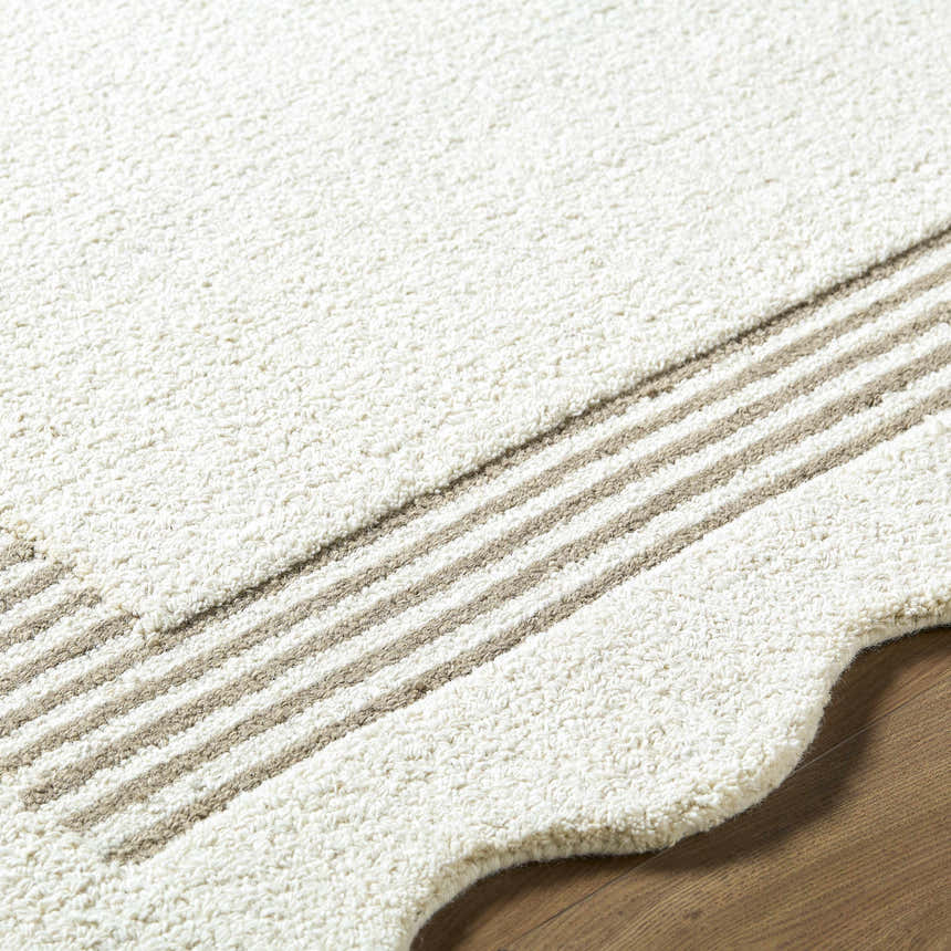 Close up of the textured Tono Ivory Border Hand Tufted Wool Area Rug with beige stripes on hardwood floor. Texture