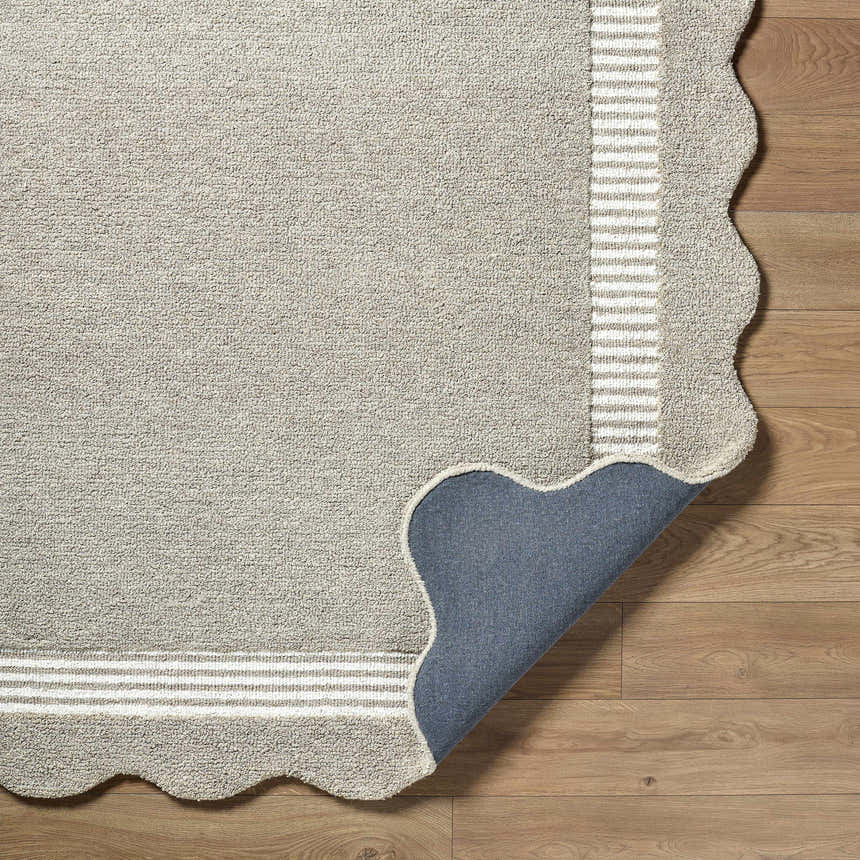 Close-up of Fanae Beige Border Hand Tufted Wool Area Rug showing texture, striped border, and scalloped edge on wood floor. Fold