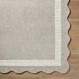 Close-up of the Fanae Beige Border Hand Tufted Wool Area Rug showing its texture, striped border, and scalloped edge. Corner