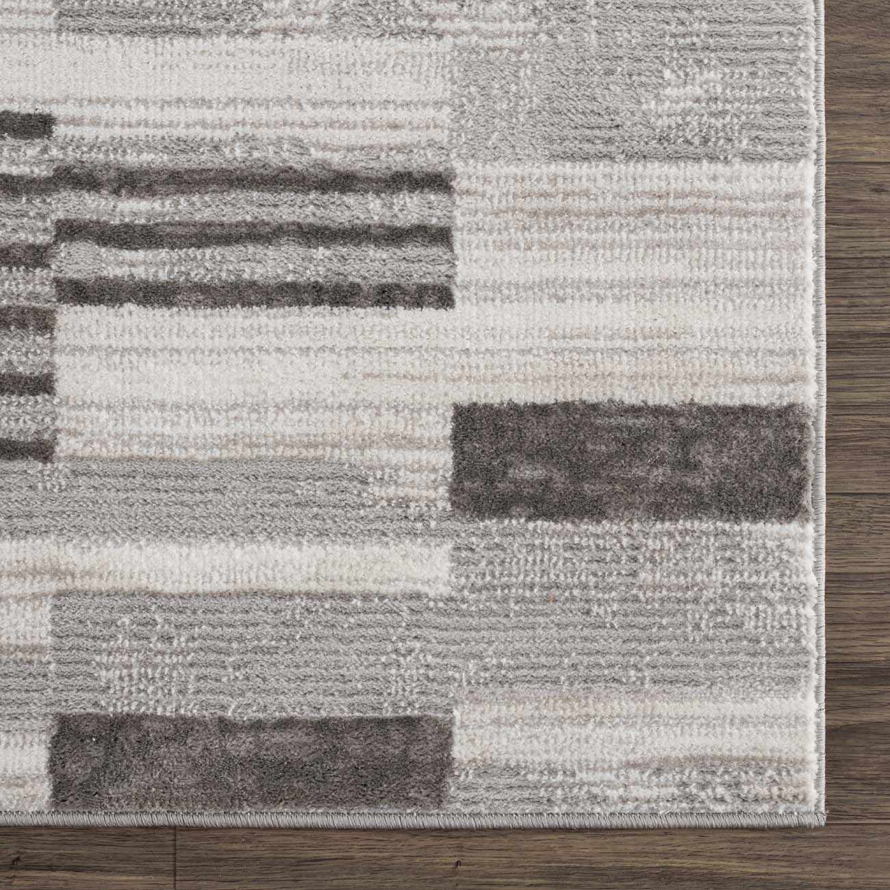 Close-up of Bronka Broken-Striped Area Rug. Geometric design in black, gray, and off-white. Machine woven texture. Swatch