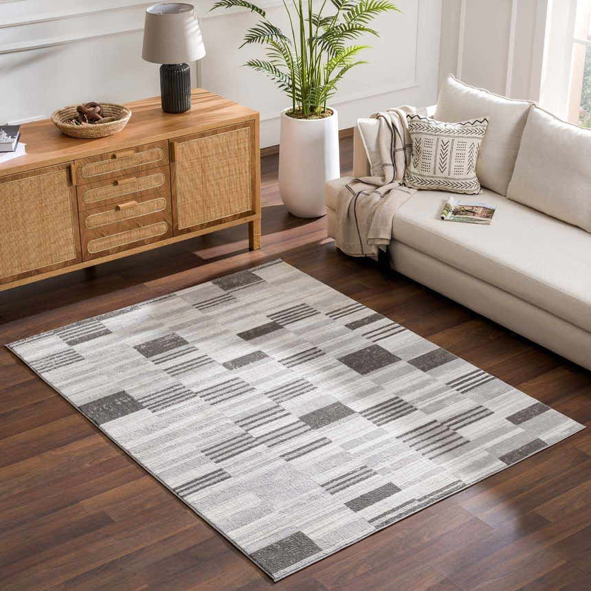 Living room with a Bronka Broken-Striped Area Rug in black, gray, and off white, complementing a neutral sofa. Roomscene-Rectangle