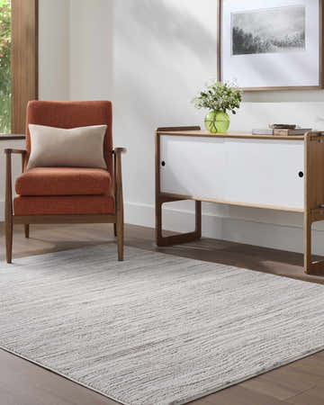 Living room scene with a light gray Bedros Area Rug, orange chair, and modern white cabinet. Roomscene-Rectangle