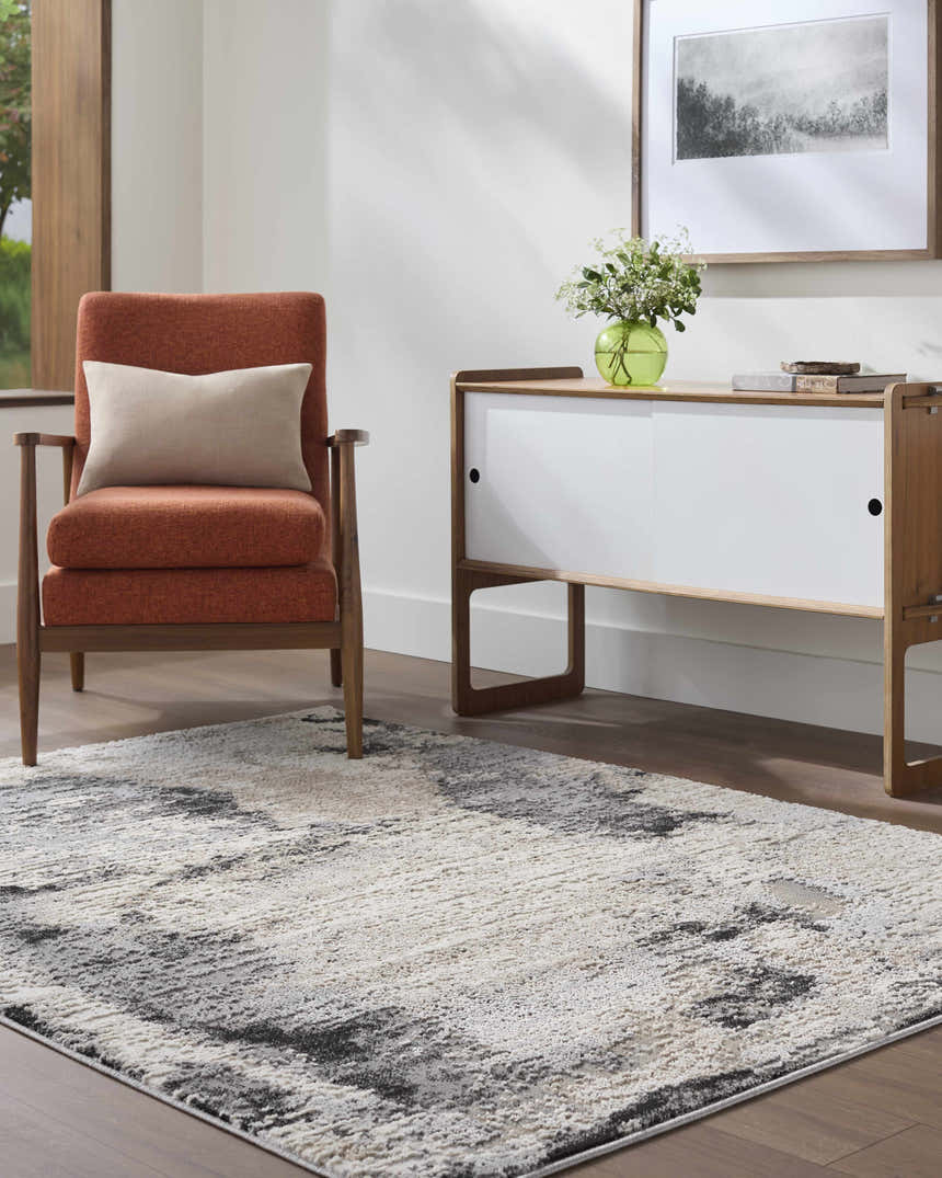 Living room scene with the ash, light silver, and silver gray Birdie Area Rug, orange chair, and white cabinet. Roomscene-Rectangle