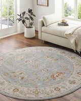 Bright living room with a round Camrose rug in light blue, beige, and brick red tones. Roomscene-Round