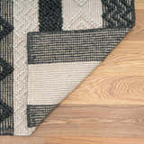 Close-up of the hand woven Whittington Black&White Wool Rug showing its texture, pattern, and backing. Fold