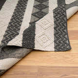 Close-up of the hand-woven Whittington Black&White Wool Rug, showing its striped, geometric design and textured wool. Fold