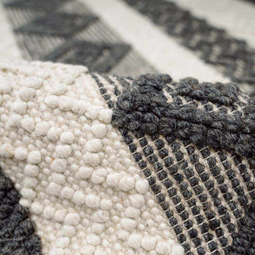 Close-up of the Whittington Black&White Wool Rug showing its textures, black geometric patterns, and ivory wool knots. Fold