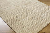 Close-up of the hand-tufted Andred Tan Area Rug. Beige, tan, and taupe wool rug with a subtle striped pattern and textured feel. Corner