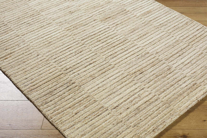Close-up of the hand-tufted Andred Tan Area Rug. Beige, tan, and taupe wool rug with a subtle striped pattern and textured feel. Corner