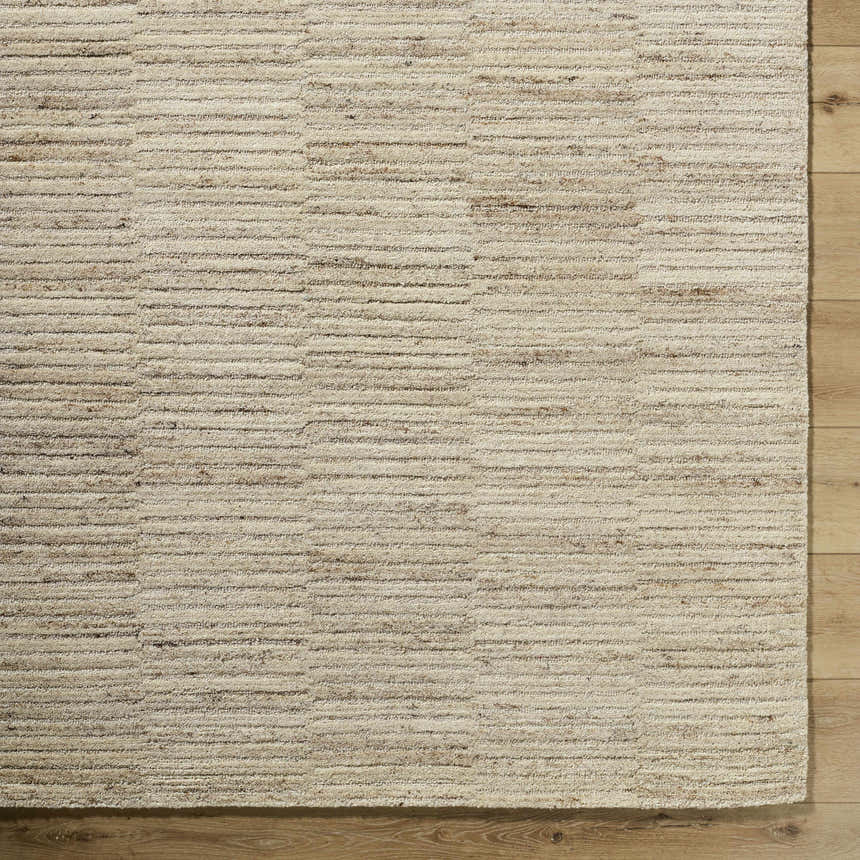 Close-up of the hand-tufted Andred Tan Area Rug. Beige, tan, and taupe wool rug with a subtle horizontal stripe pattern. Corner