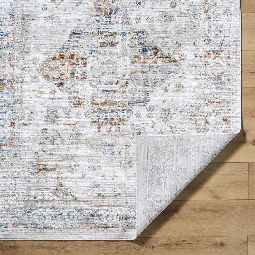 Close-up of the Cargan Area Rug showing its traditional burnt orange, cream, and navy pattern and machine-woven texture. Fold