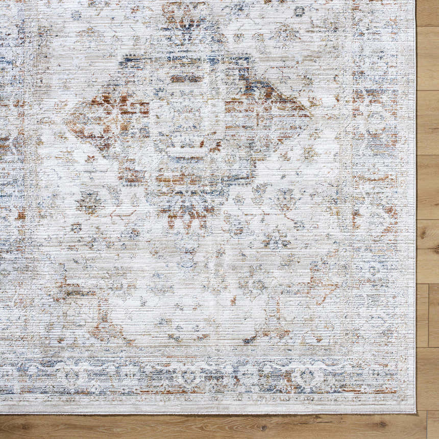 Close-up of the Cargan Area Rug. Traditional design in cream, burnt orange, navy, and tan on a wood floor. Corner