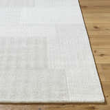 Close-up of the beige Camila Area Rug showing its subtle texture and pattern on a wood floor. Front