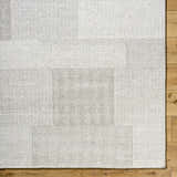 Close-up of the Camila Beige Area Rug showing its subtle geometric pattern and wool texture on a wood floor. Corner
