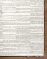 Close up of the ivory Carlen shag rug showing texture and subtle horizontal stripes on a wood floor. Corner