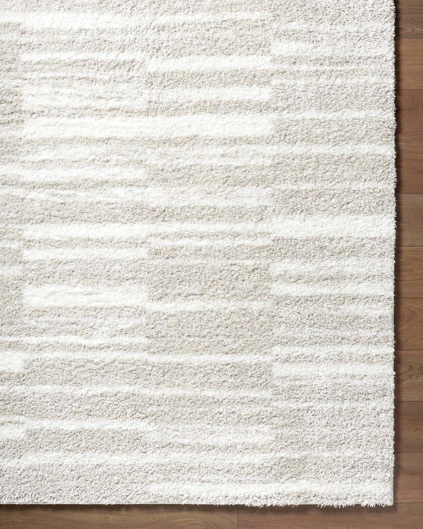 Close up of the ivory Carlen shag rug showing texture and subtle horizontal stripes on a wood floor. Corner