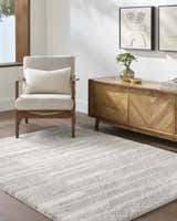 Living room scene with an ivory armchair, wood cabinet, and the soft, ivory Carlen Area Rug. Roomscene-Rectangle