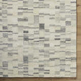 Close-up of the Max Handmade Becki Owens x LIVABLISS rug. Wool rug features a contemporary geometric block pattern in ivory, gray, and charcoal. Corner
